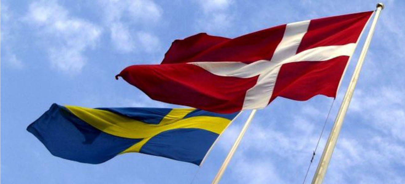 Svenska och danska flaggan vajjar i vinden bredvid varandra.