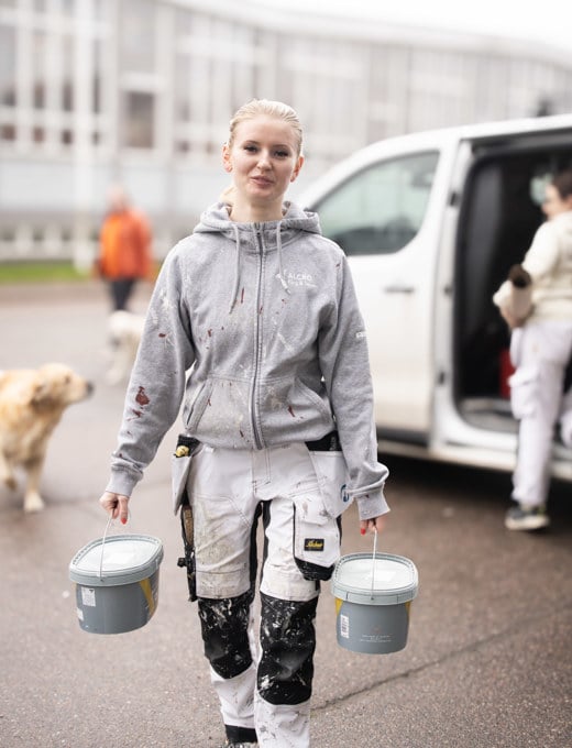 Kvinnlig målare bär två färgburkar