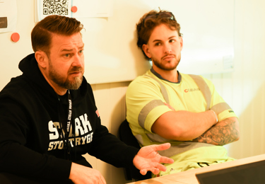 Byggnads ordförande Kim Söderström och byggnadsarbetare i en byggbod