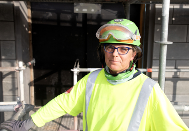 Person med varselkläder och grön hjälm.