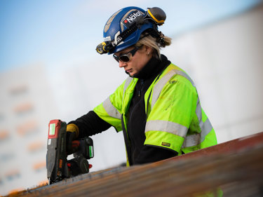 Byggnadsarbetare som använder ett handverktyg