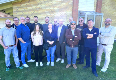 Män och kvinnor längst en tegelvägg.