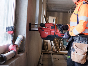 Arbetare som borrar i vägg med borrhammare