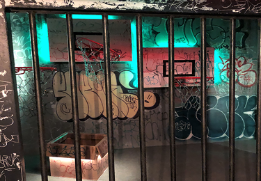 Graffittivägg bakom galler.