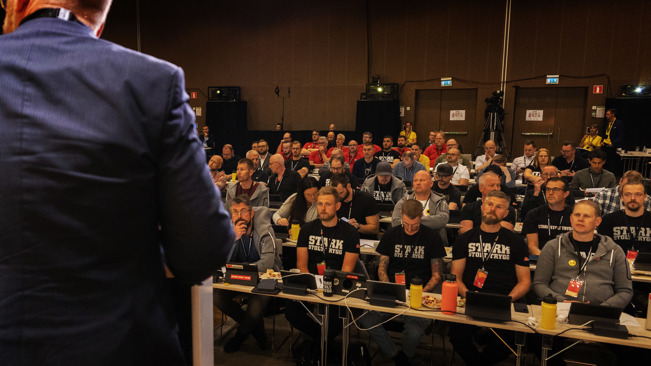 Kongresshall med delatgare som lyssnar på talare