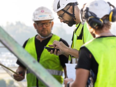 Tre byggnadsarbetare tittar på en mobiltelefon