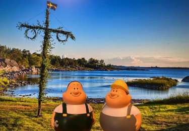 Bild på två byggnadsarbetare framför en midsommarstång