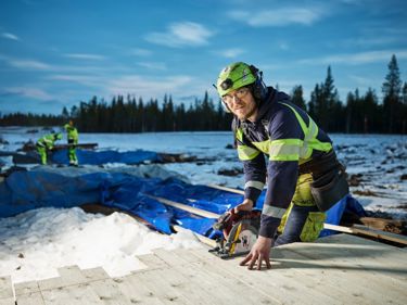 En person som arbetar med verktyg, har på sig arbetskläder och hjälm.