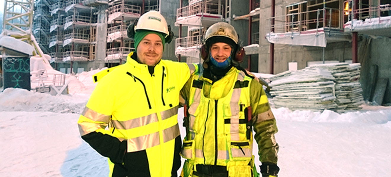Två byggnadsarbetare på en snöig byggarbetsplats.