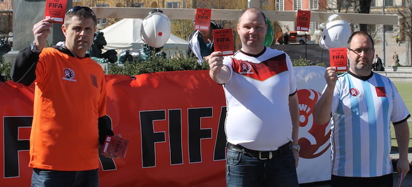 Tre personer håller upp röda kort i protest mot Fifa